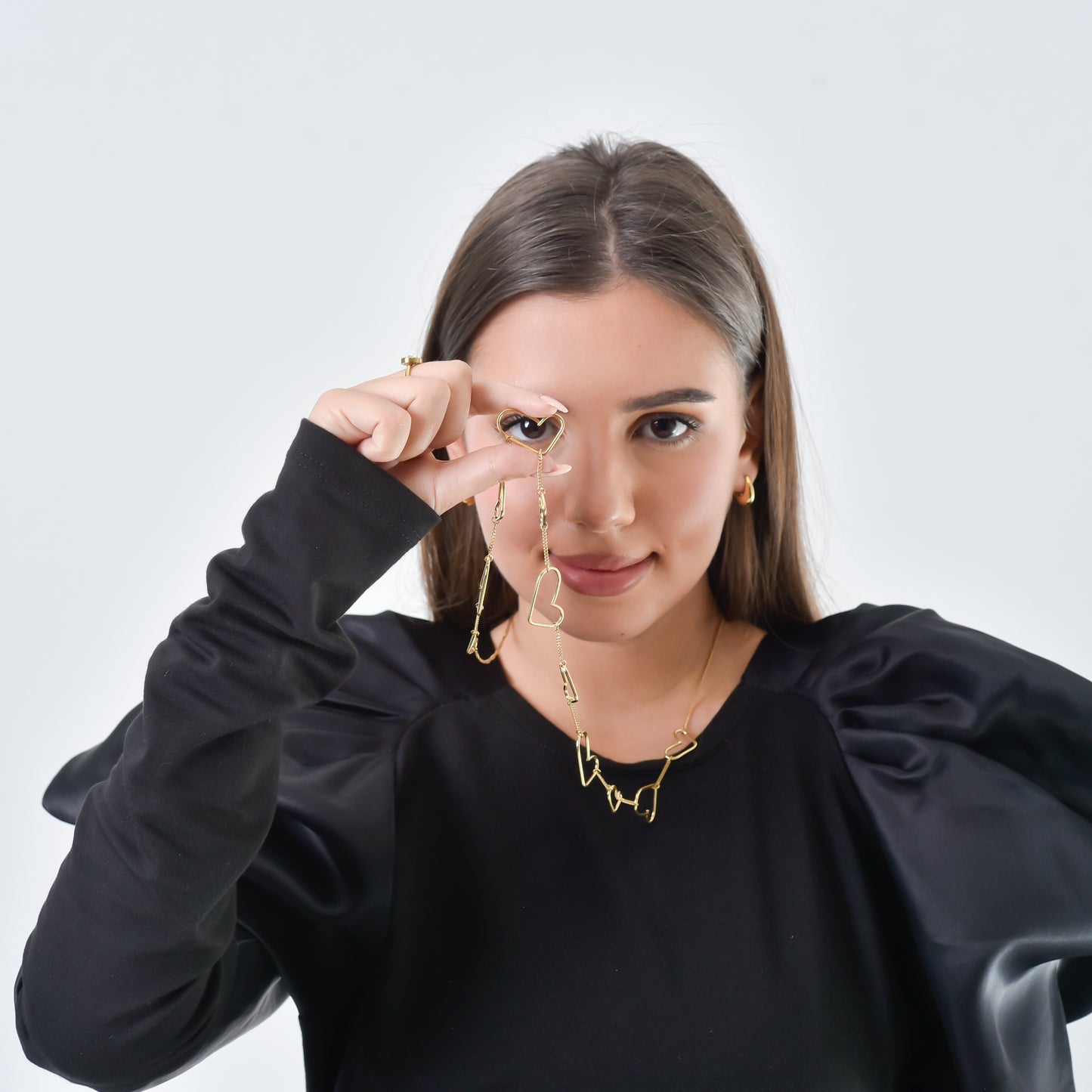 Woman wearing gold earrings and a necklace against a white background