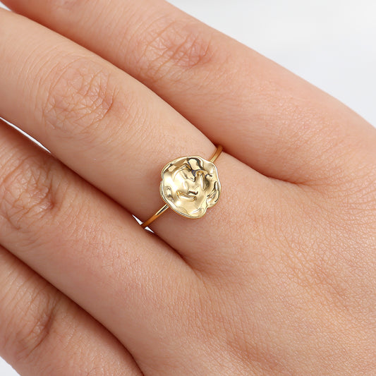 Gold ring on a person's finger with a plain background