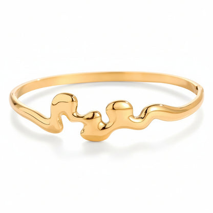 Gold-plated sculptural wave bangle with organic fluid design and side clasp closure