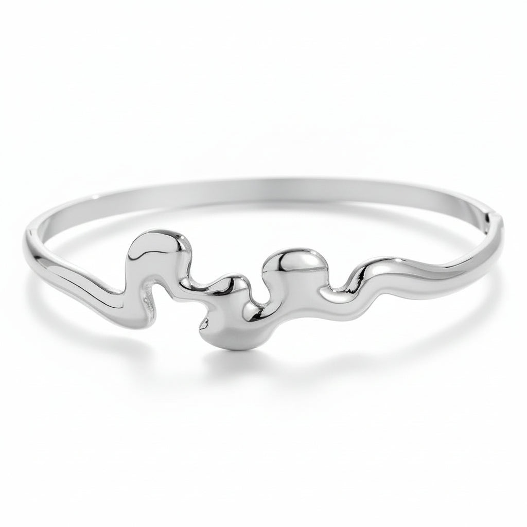 White gold-plated sculptural wave bangle with organic fluid design and side clasp closure