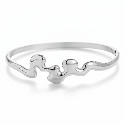 White gold-plated sculptural wave bangle with organic fluid design and side clasp closure
