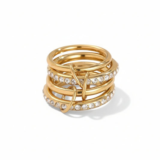 Stack of gold rings with embedded diamonds on a light gray background
