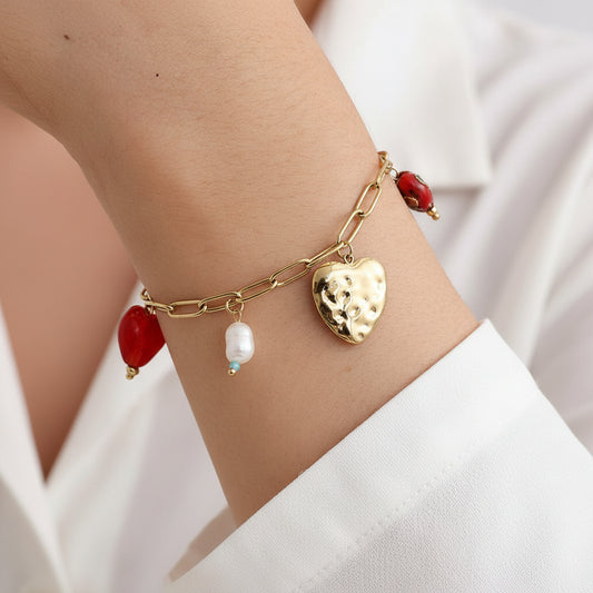 Wrist wearing gold chain bracelet with multiple heart charms and pearl visible. Narukvica.