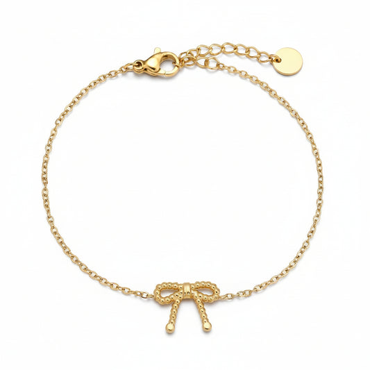 Gold beaded bow bracelet on delicate chain embodying quiet feminine grace