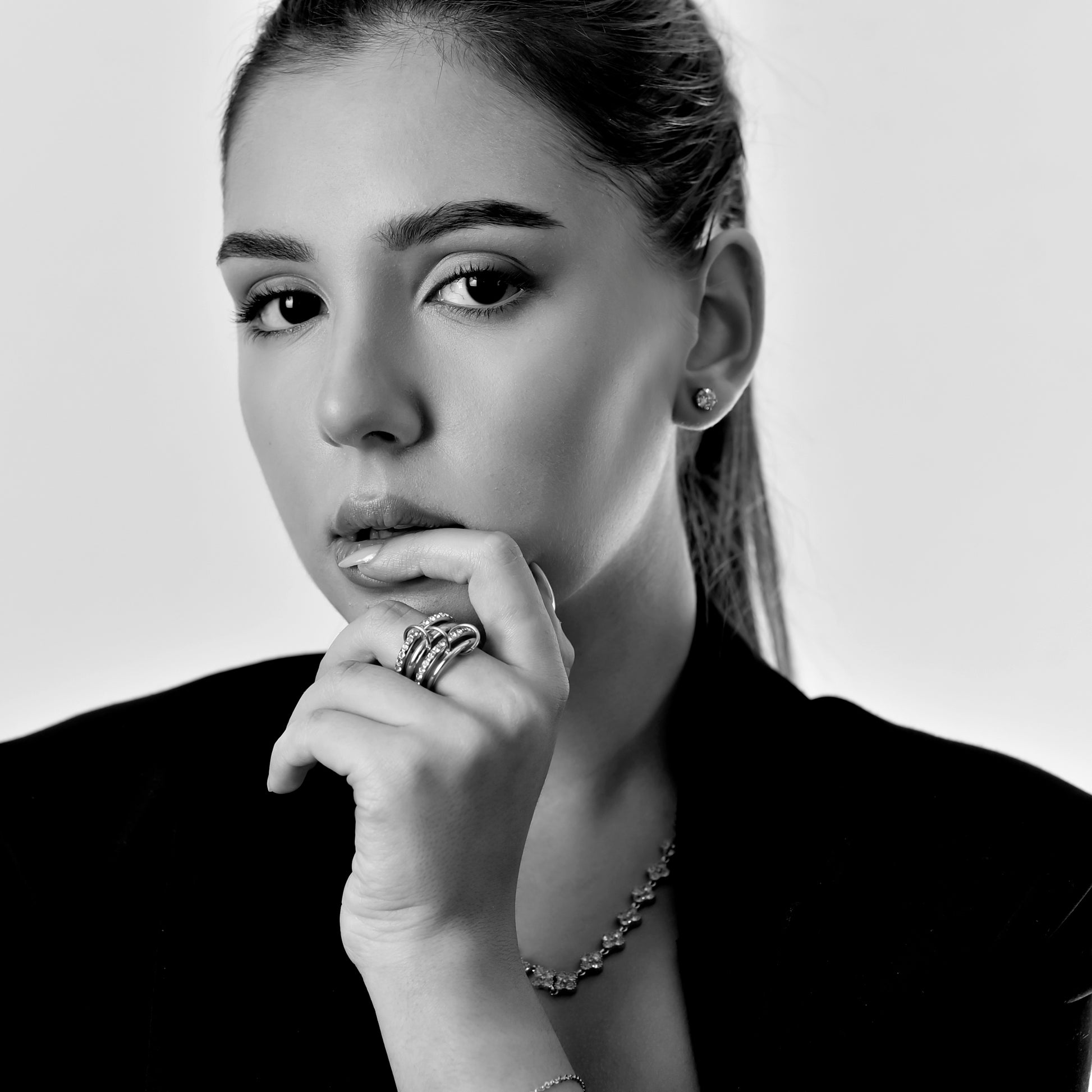 Black and white portrait of a woman with jewelry on a plain background