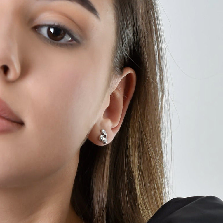 Close-up of a woman wearing silver earrings with a plain background