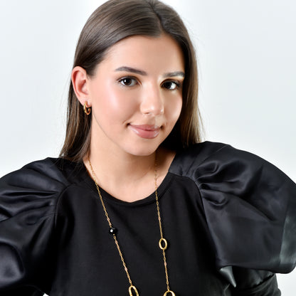 Woman wearing a black top and gold necklace against a white background