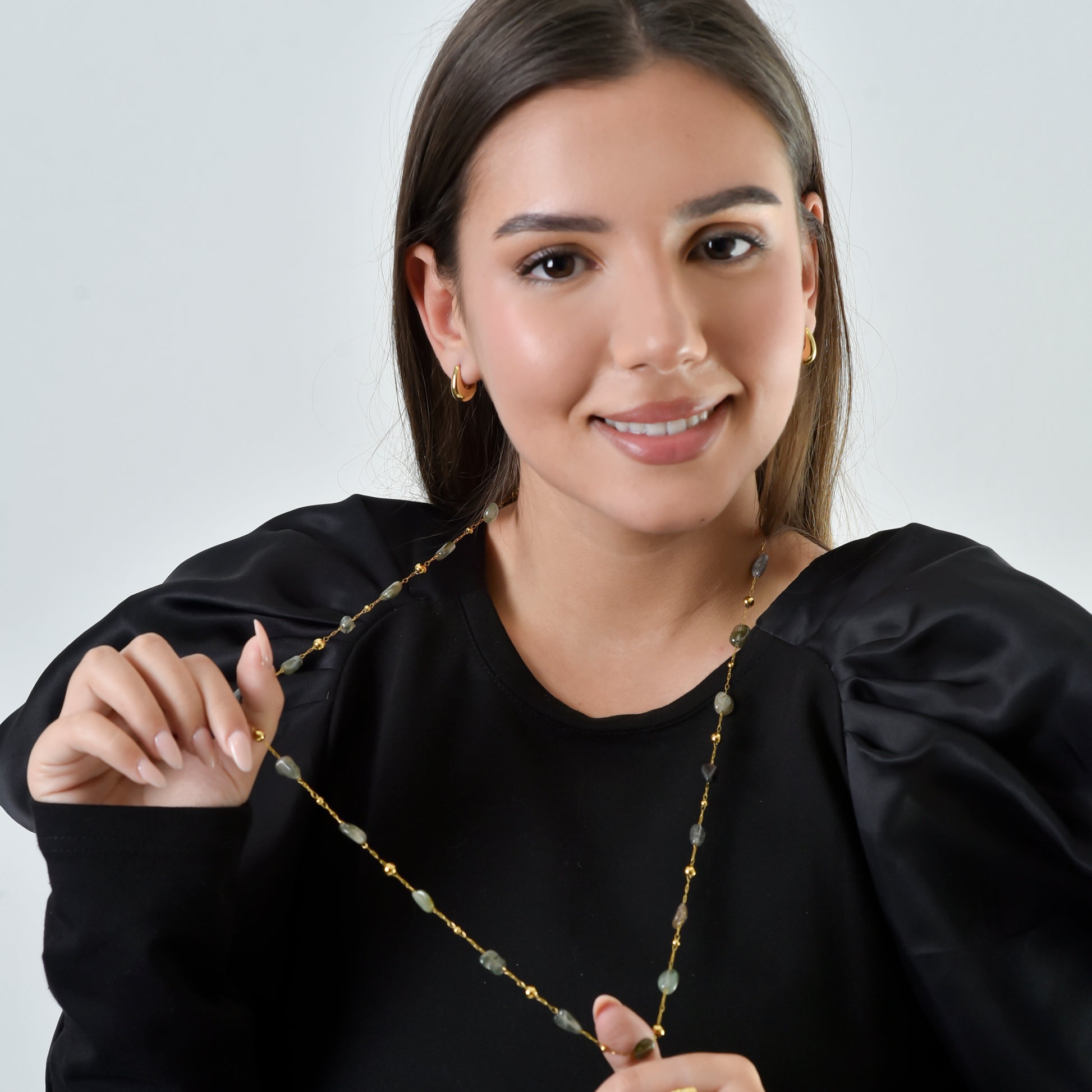 Woman holding a necklace with a plain background