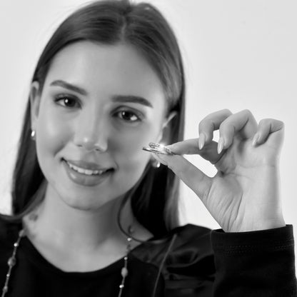 Woman holding a diamond ring close to her face against a plain background