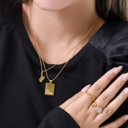 Close-up of a person wearing gold necklaces and rings on a black background
