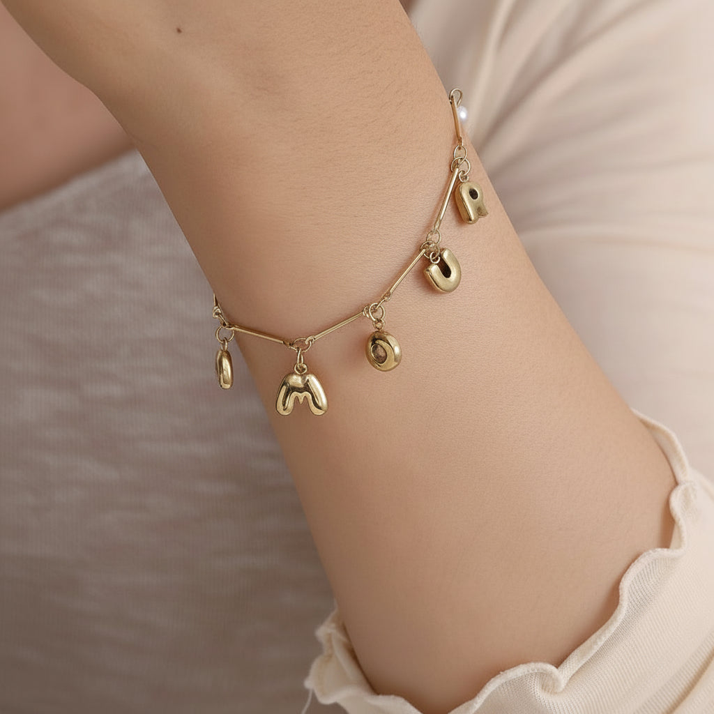 Gold spelled in love bracelet worn on wrist showing AMOUR letter charms and pearls