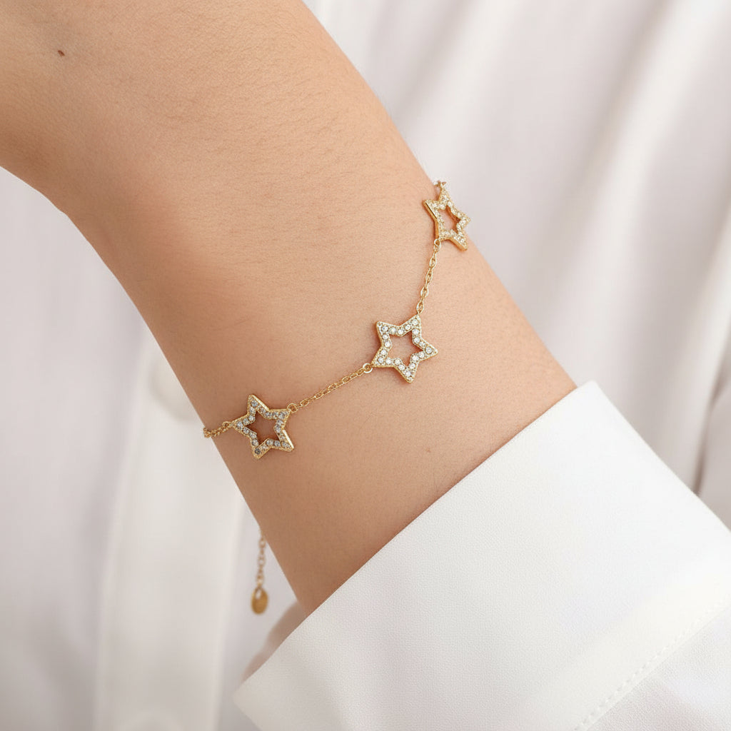 Gold star bracelet on a person's wrist with a neutral background