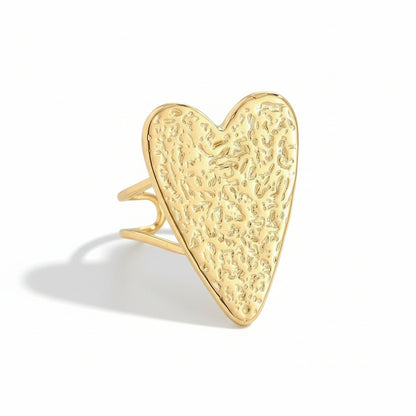 Gold heart-shaped ring on a light gray background
